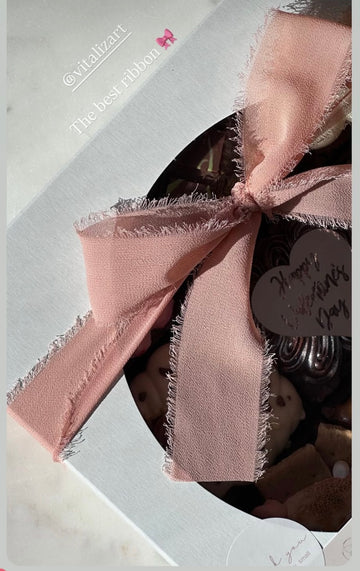 Blush frayed ribbon bow on a dessert gift box