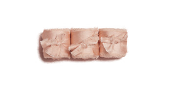 Three blush frayed ribbon rolls tied with bows