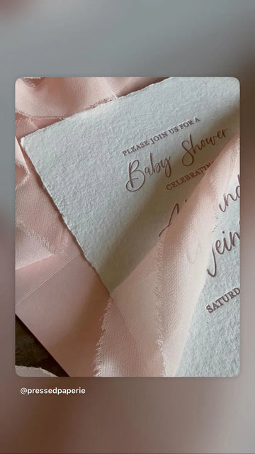 Baby shower invitations styled with blush pink frayed ribbon