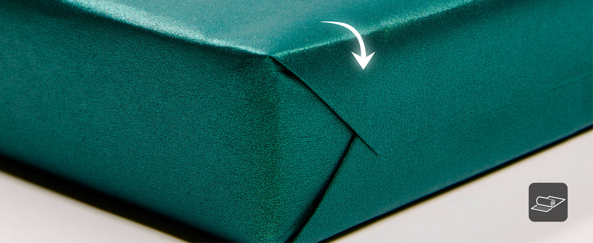 Close-up of green pearly wrapping paper folded back to show its shiny face and matte underside