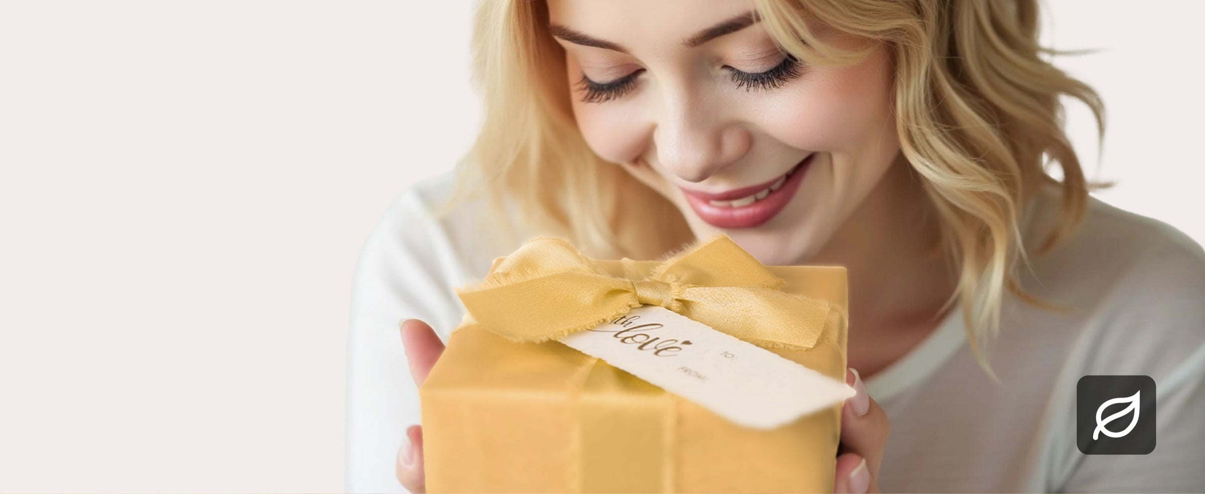 Recipient opening a gift wrapped in gold pearly paper with matching satin ribbon