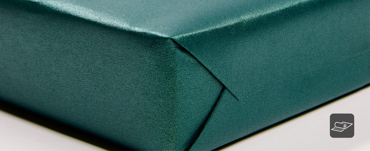 Close-up of pearly teal green wrapping paper folded back to show both shimmering surfaces