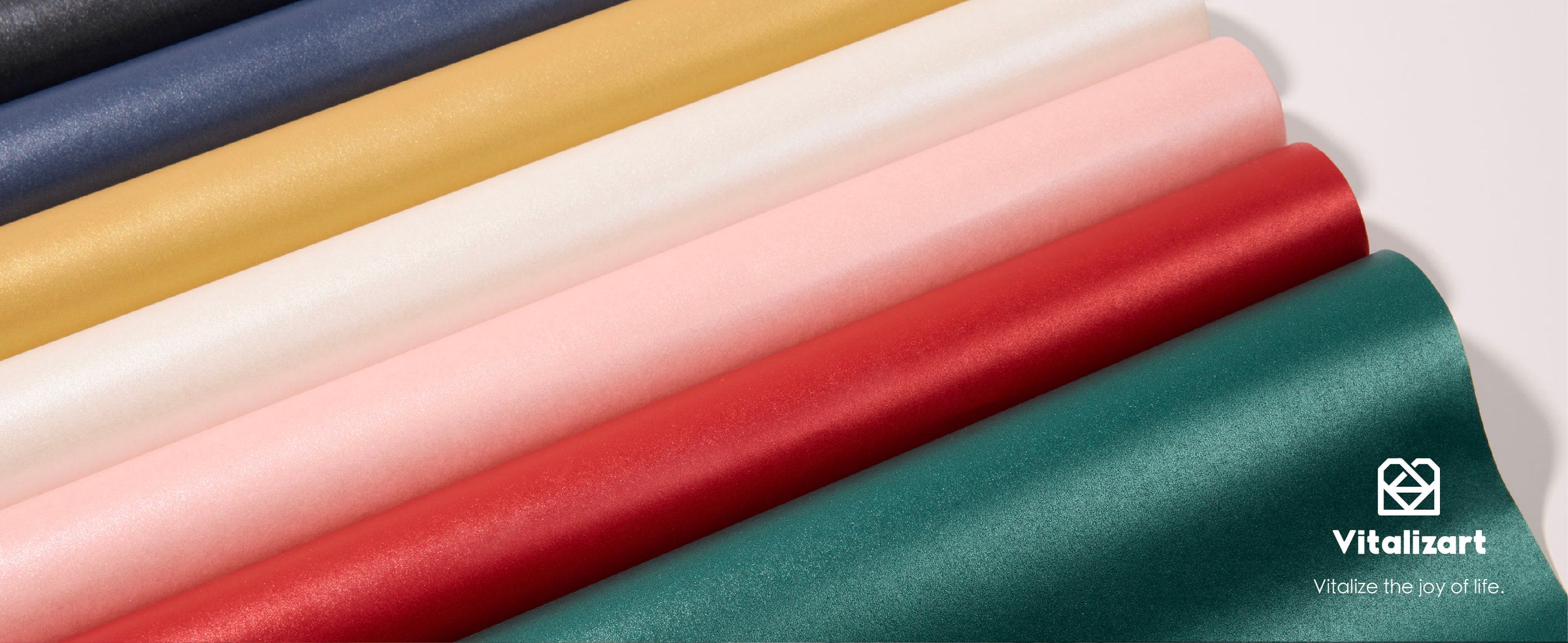 Diagonal rolls of pearly wrapping paper in black, navy, gold, white, pink, red, and teal