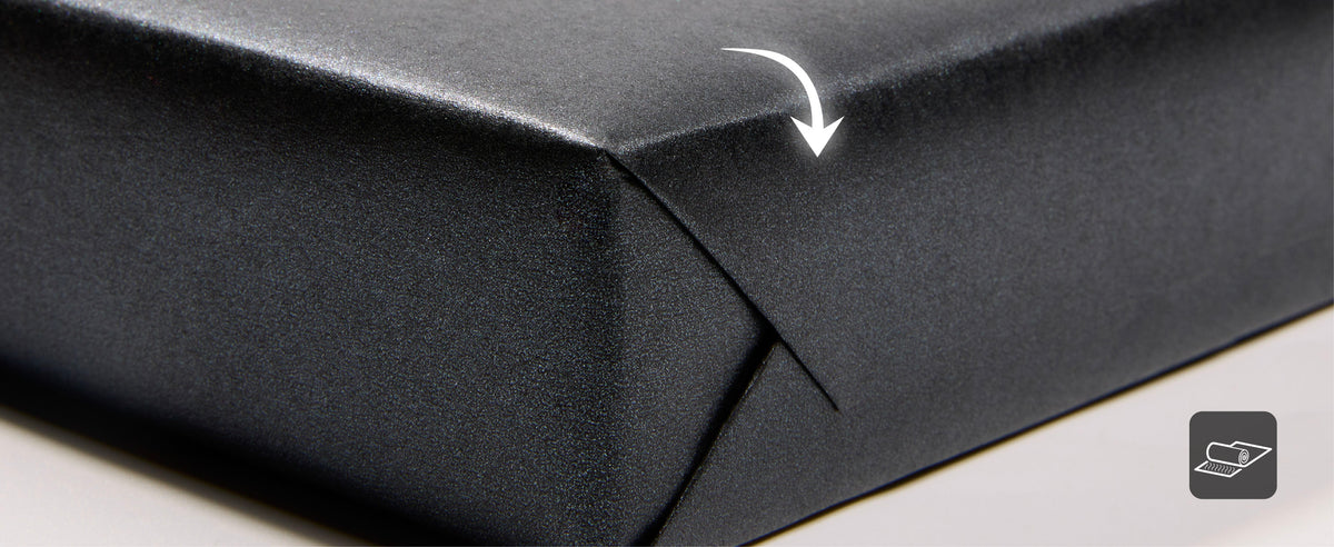 Dark charcoal wrapping paper folded back to show its reverse side and fine pearly shimmer