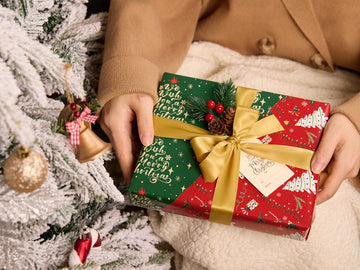 Christmas gift wrapped in red and green paper with a gold satin ribbon
