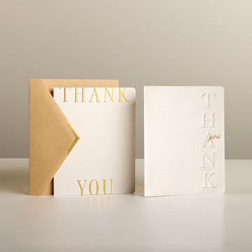 White embossed thank-you cards with gold lettering and kraft envelopes