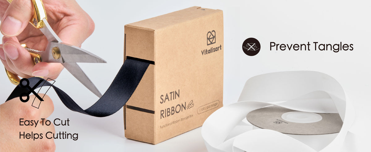 Black satin ribbon feeds from a cardboard dispenser while a hand cuts it with scissors.