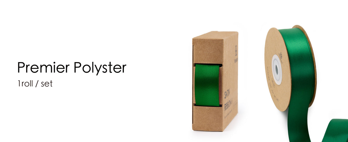 Green satin ribbon on a kraft spool beside a matching cardboard dispenser box