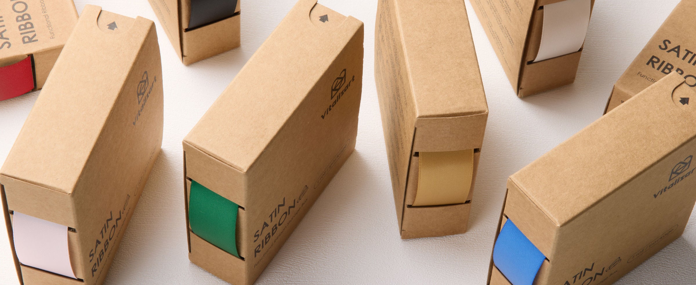 Cardboard satin ribbon dispensers display red, black, white, green, gold, and blue ribbon options.