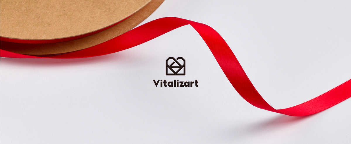 Glossy red satin ribbon unwinding from a kraft spool, with a close view of its woven texture