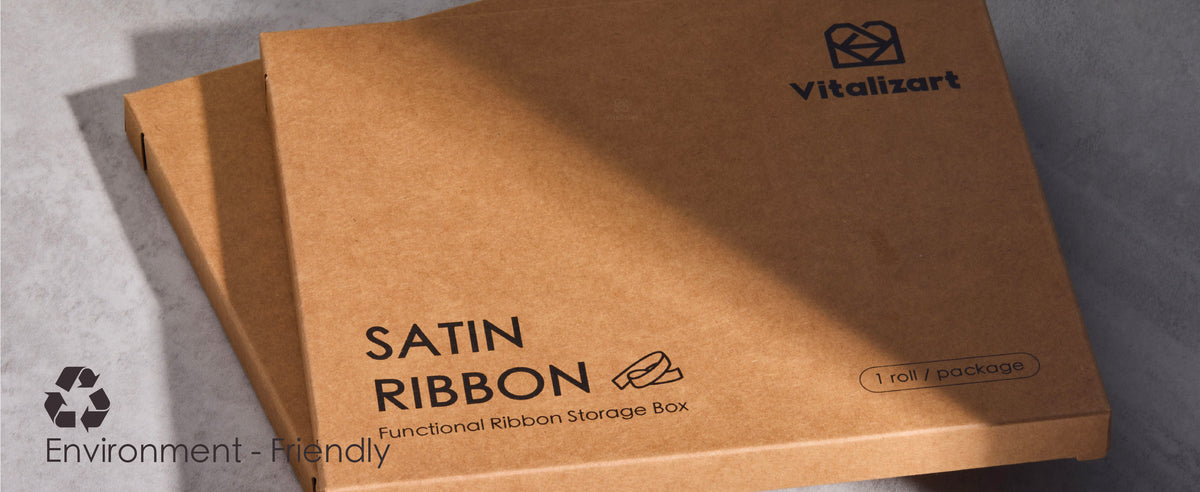 Three kraft satin ribbon storage boxes stacked on gray fabric beneath diagonal sunlight and shadows.