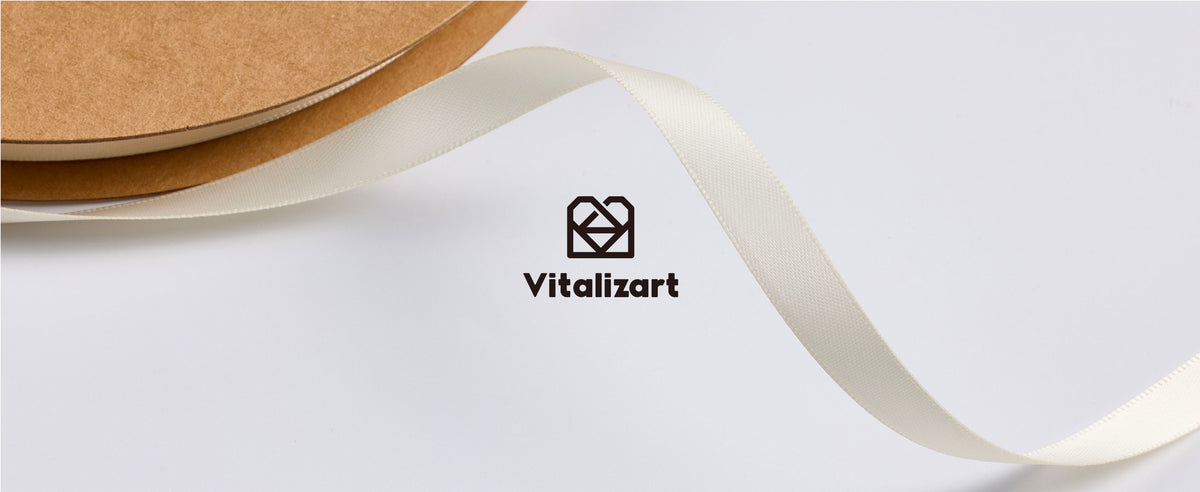 Ivory satin ribbon unfurling from a brown cardboard spool with Vitalizart branding