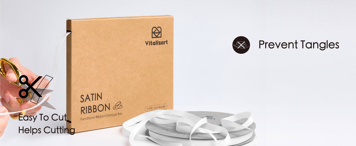 Off-white satin ribbon feeds from a kraft dispenser box as a hand cuts it with scissors