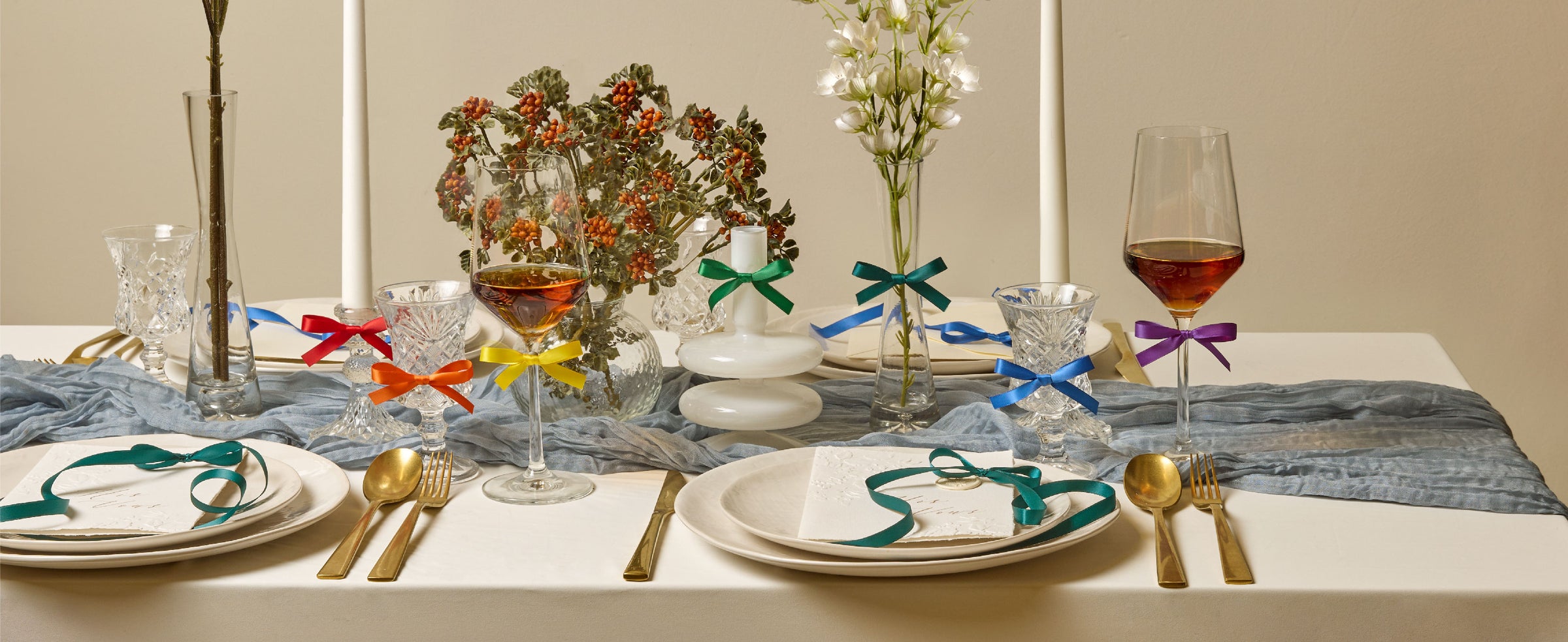 Rainbow double-faced satin ribbon set arranged across a styled dining table with gifts and floral accents