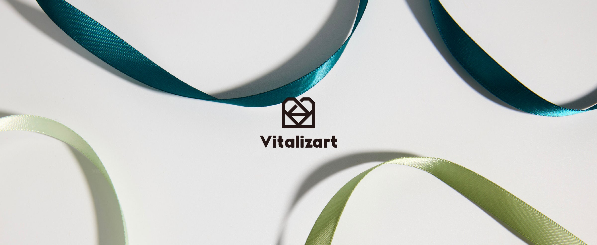 Looped strands from the mint and sage double-faced satin ribbon set displayed in coordinated tonal colors