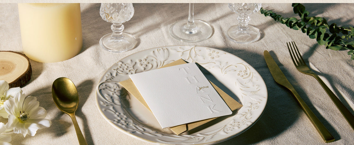 White embossed thank-you card used as a place card in an elegant table setting