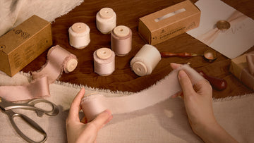 Hands measuring and cutting blush frayed ribbon