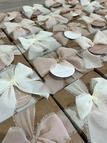 Small favor boxes tied with ivory and blush ribbon bows