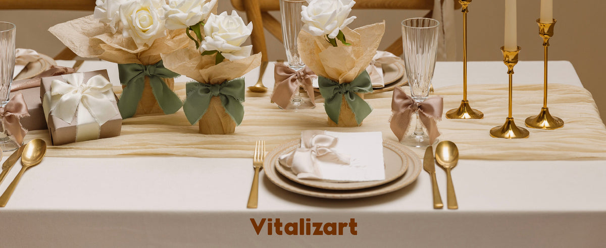 Neutral table setting with ribbon-tied white rose arrangements, stemware, and a wrapped gift