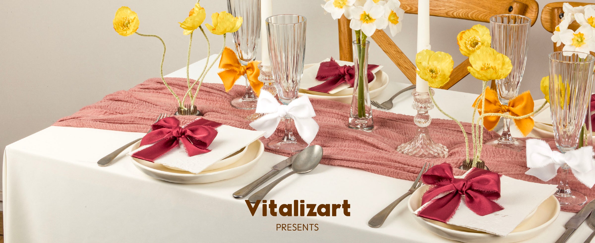 Burgundy, orange, and white satin bows decorate a pink and yellow floral table setting