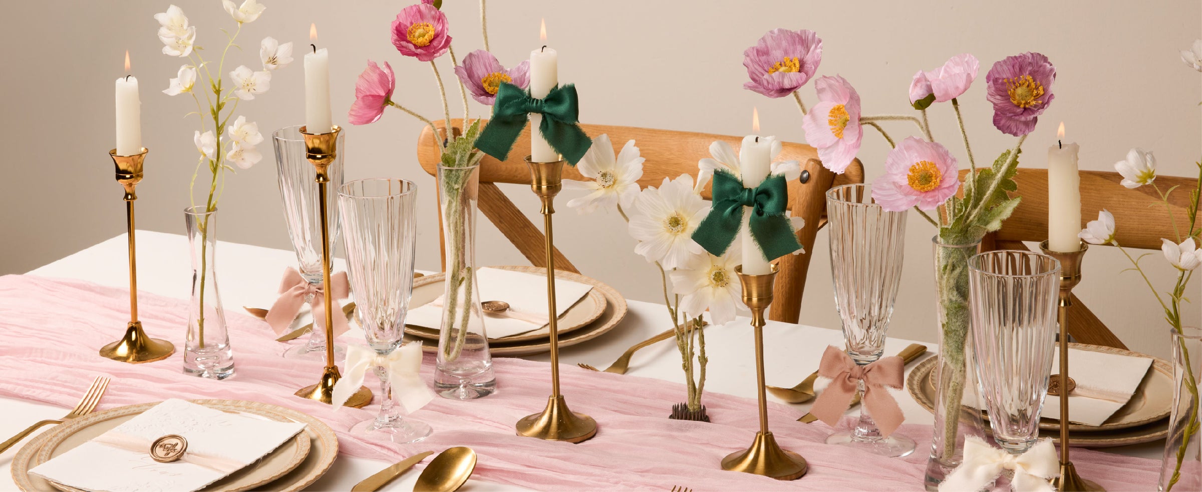 Dark green satin ribbon bows decorate candles on a floral table set with gold accents