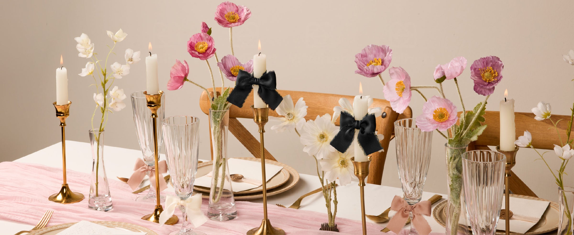 Black frayed satin ribbon bows accent candles in a floral table setting with blush and ivory bows.