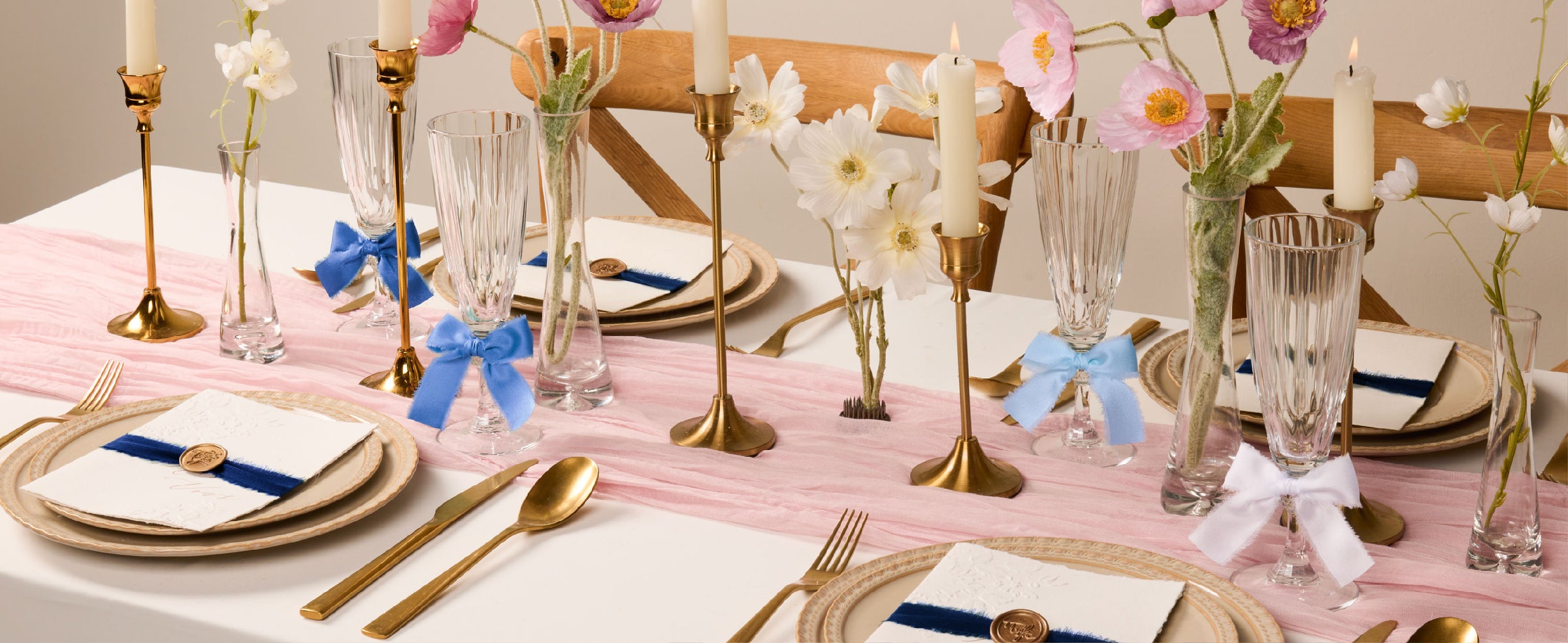 Blue and white frayed satin ribbons decorate glassware and place cards on a floral dining table.