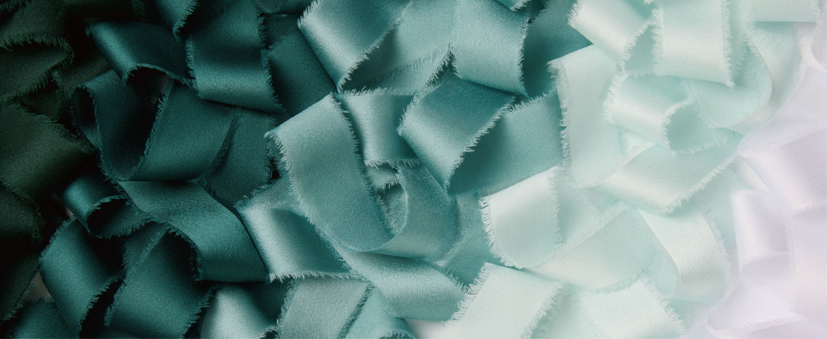 Loose frayed-edge satin ribbon in forest green, teal, sage, pale mint, and white.