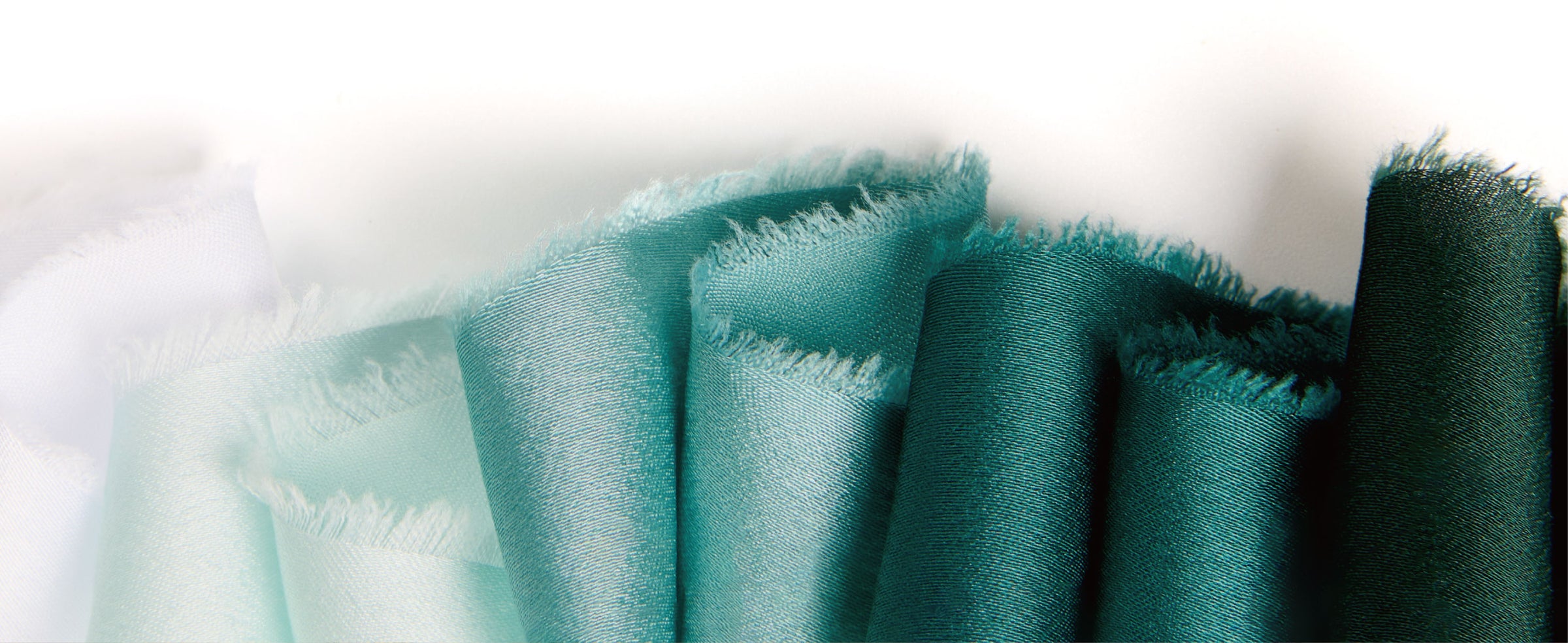 Folded frayed-edge satin ribbon samples progressing from pale mint and sage to dark green.