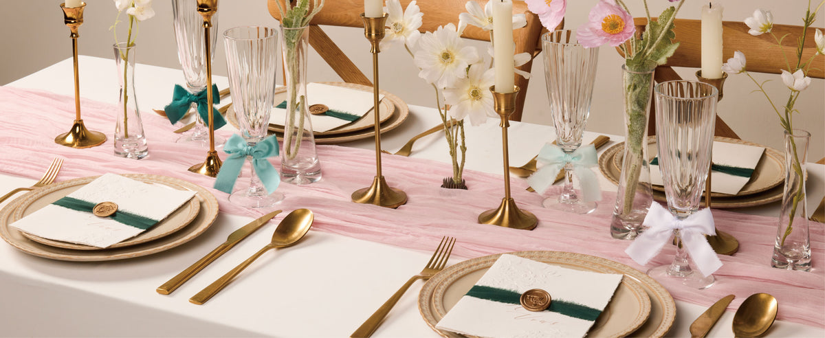 Green, mint, and white frayed satin ribbons decorate glassware and place cards on a dining table.