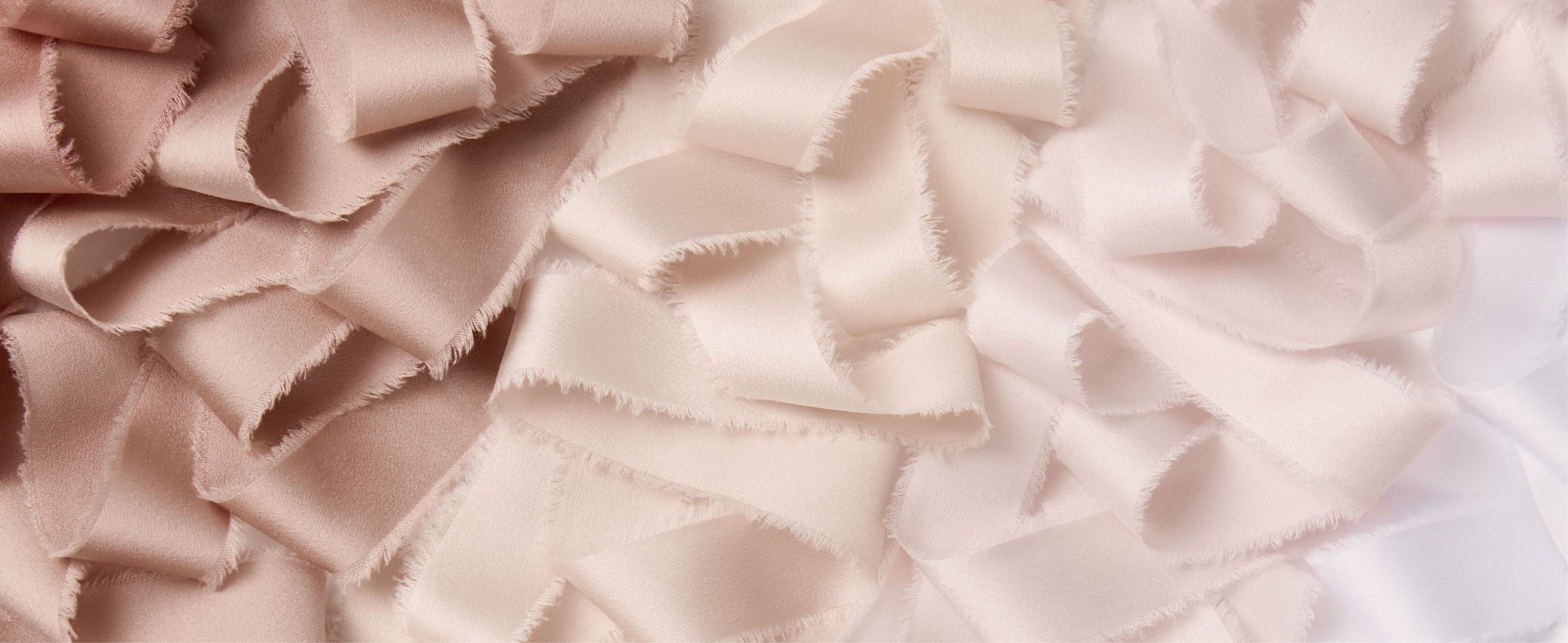 Nude, ivory, and white satin ribbons layered in loose folds with soft frayed edges.