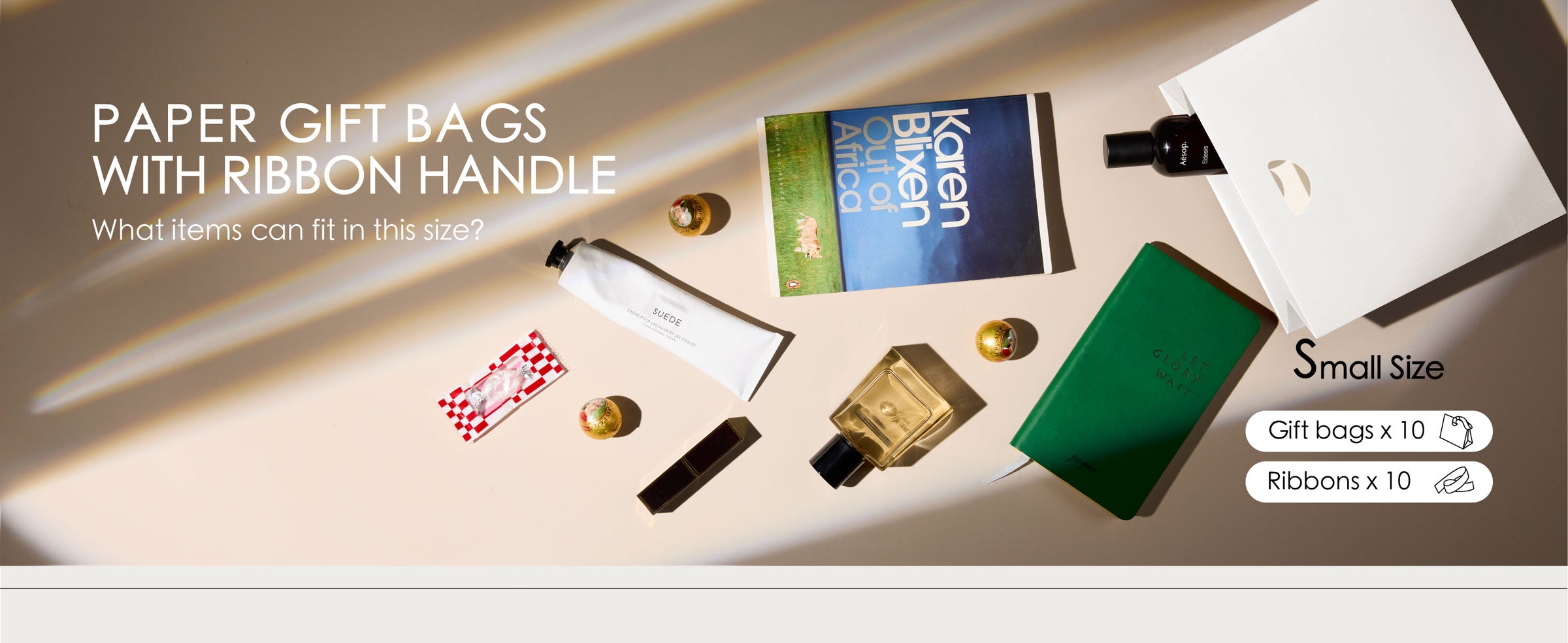 White small paper gift bags with ribbon handles styled beside gifts, cards, and small accessories