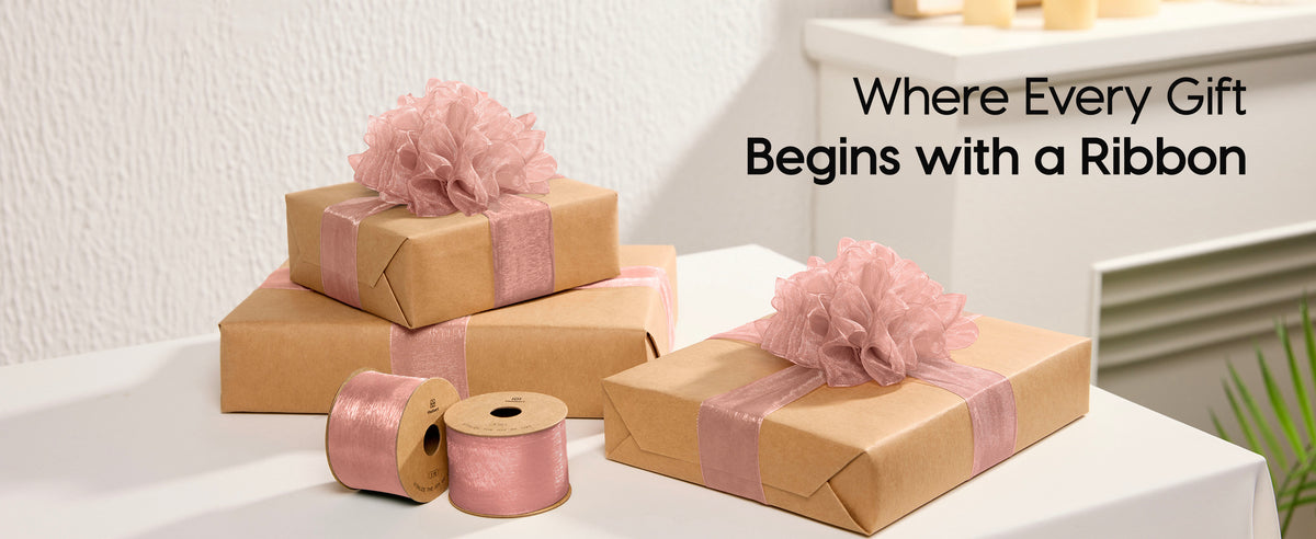 Kraft-paper gifts decorated with dusty rose organza ribbon and large layered bows beside two spools