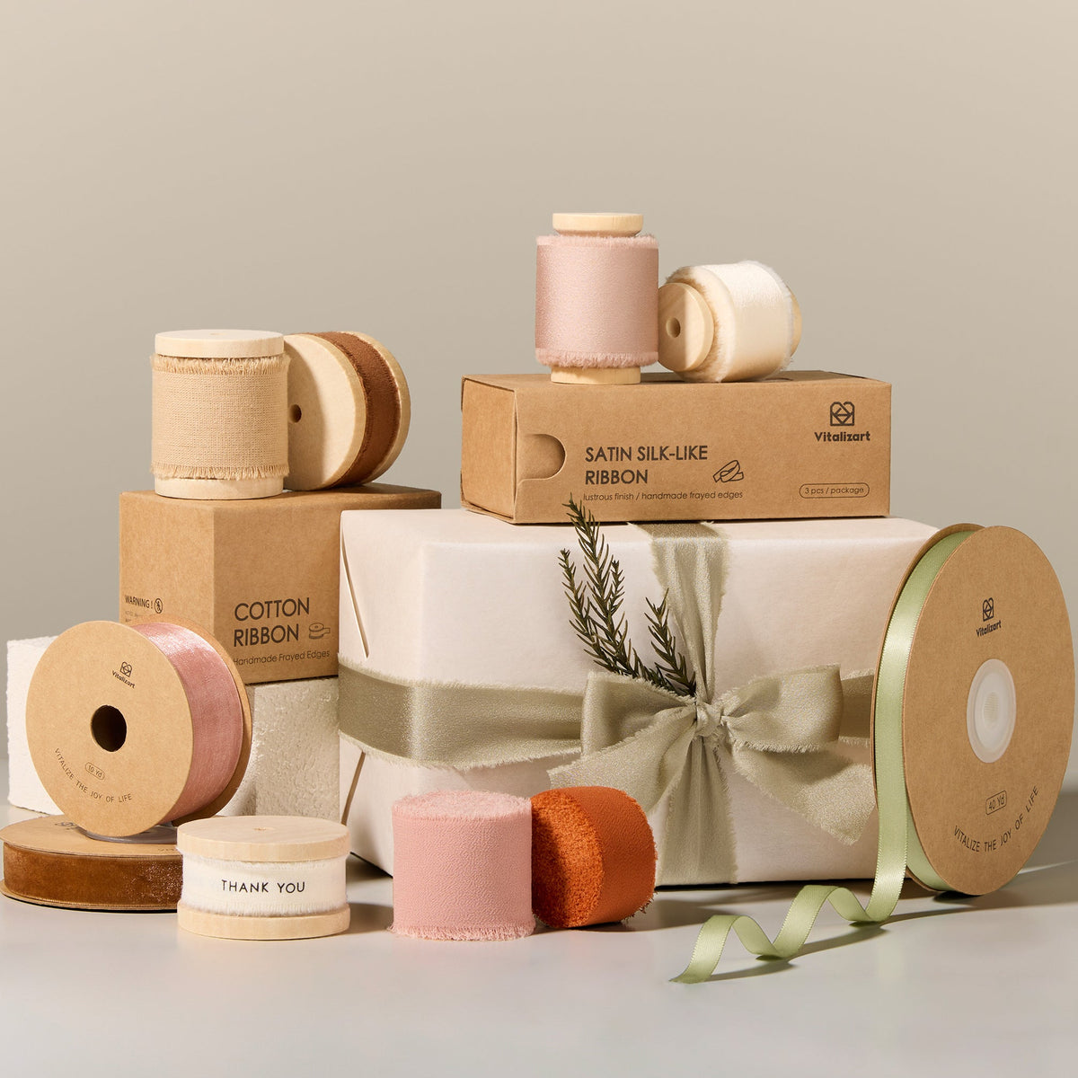 Vitalizart ribbon spools surrounding a gift box tied with sage ribbon
