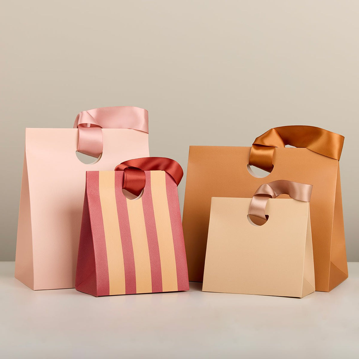 Pink and orange paper gift bags with satin ribbon handles