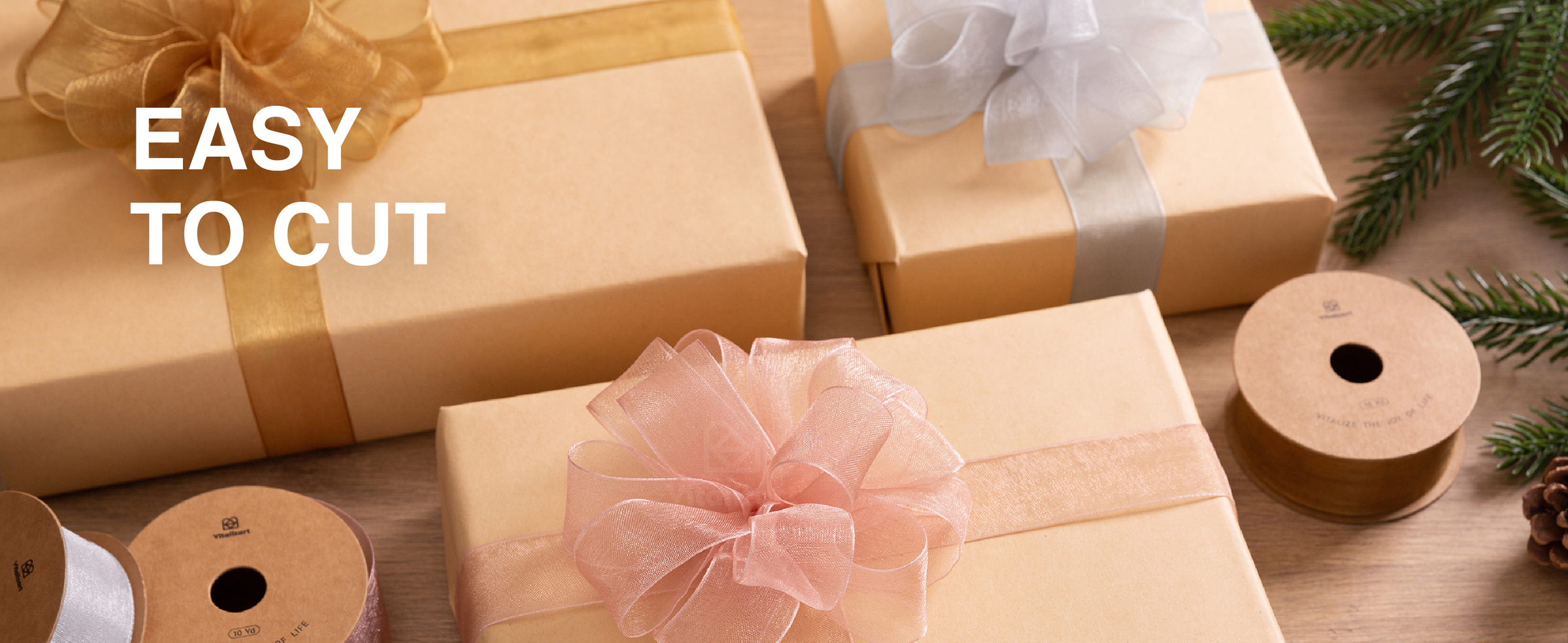 Sheer ribbon bows decorate a candlelit Christmas table with evergreen garland and wrapped place settings.