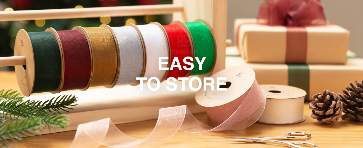 Kraft gifts tied with shimmering organza ribbons beside snowy miniature trees and Christmas décor.