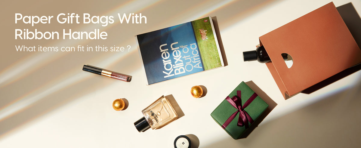 Open copper-brown paper gift bag beside a book, perfume, cosmetics, jar, bottle, and wrapped gift