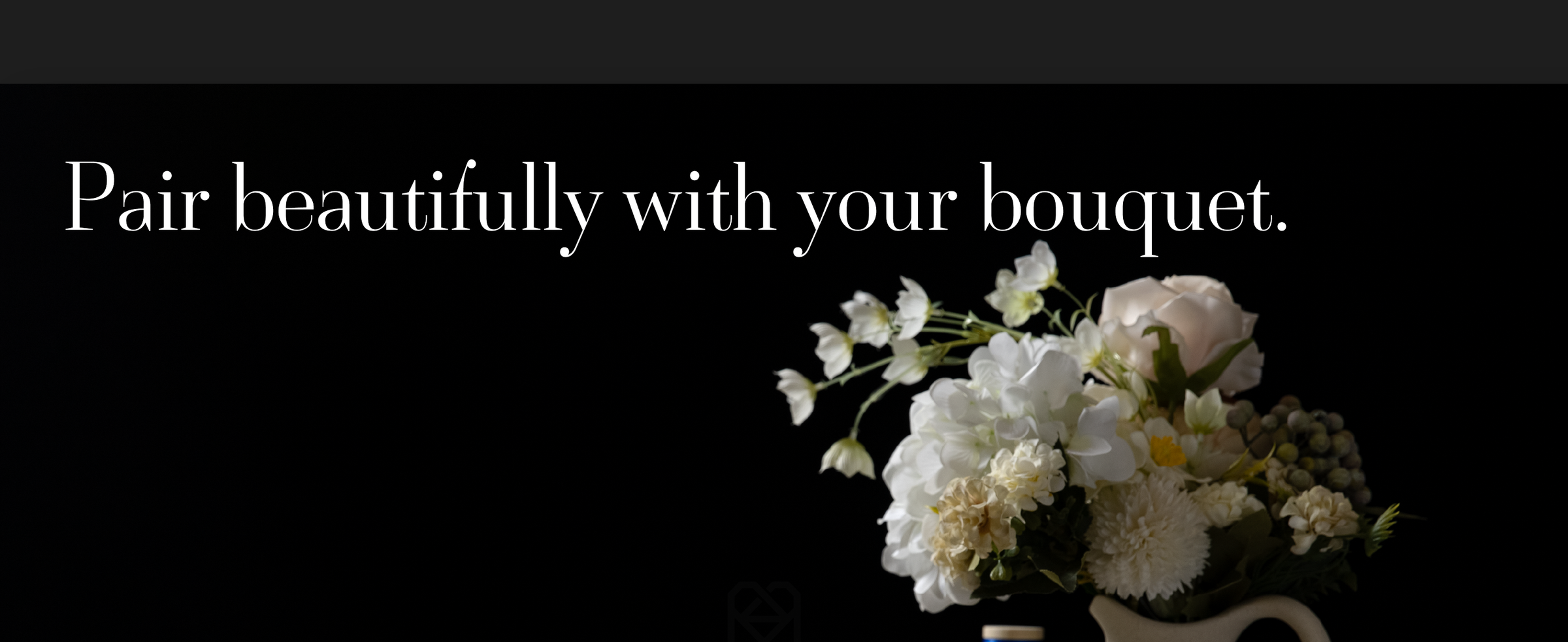 Pink and yellow satin ribbons decorate an open book beside a white bouquet in a ceramic pitcher.