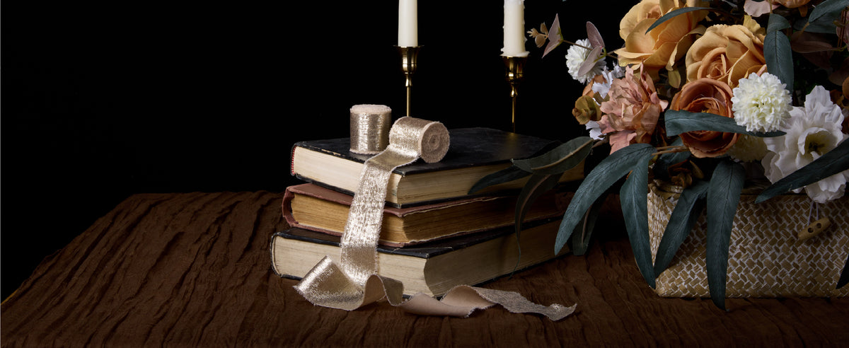 Light nude metallic chiffon ribbon styled with flowers, candles, and a tabletop gift display