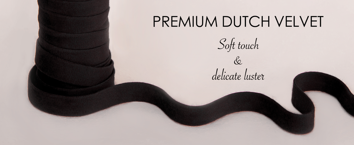 Close-up of black velvet ribbon with a soft pile and pinked edge on white fabric