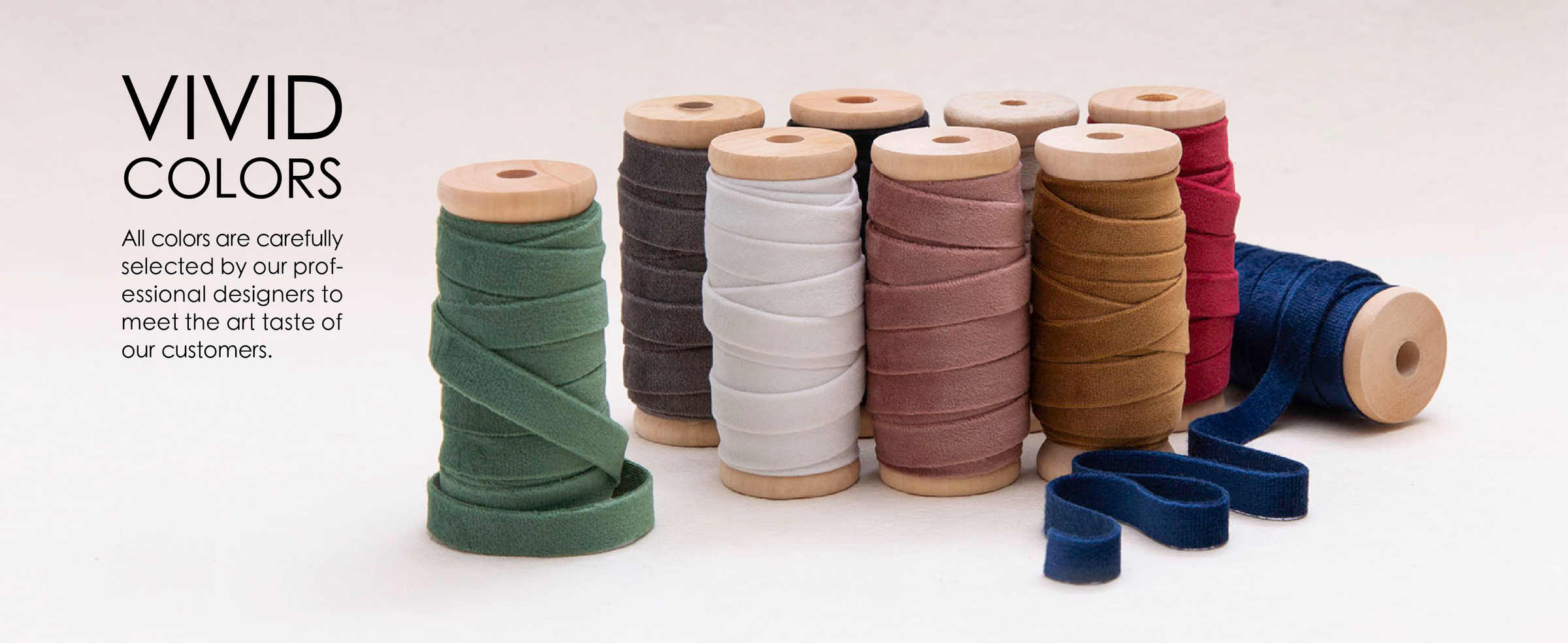 Wooden spools display velvet ribbon in green, charcoal, white, pink, brown, burgundy, and navy