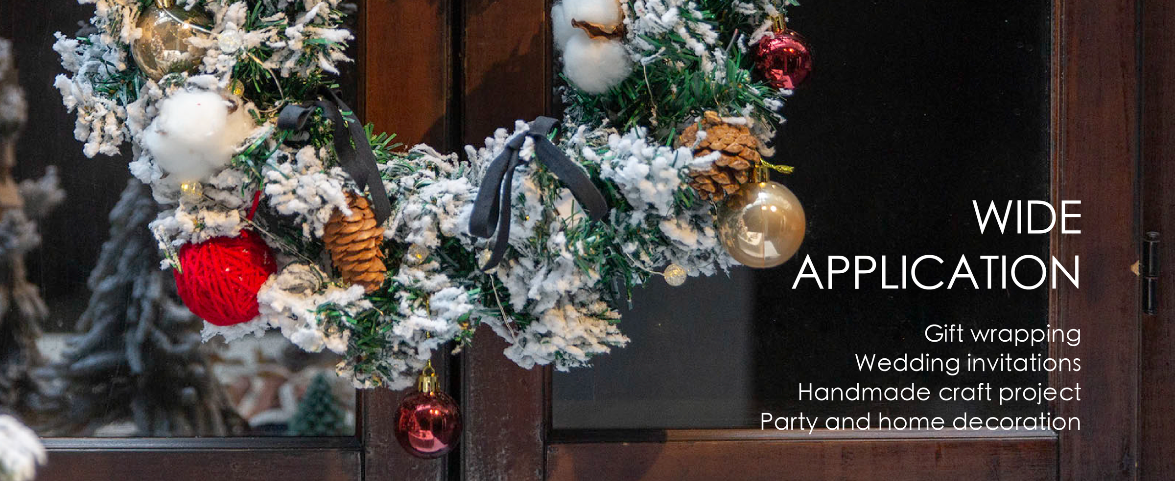 Black velvet bows decorate a snowy evergreen wreath with pinecones, lights, and ornaments