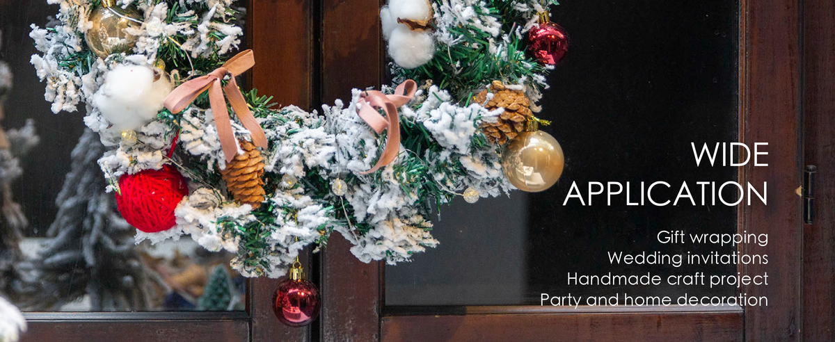 Rose velvet ribbon bows decorate a snowy evergreen wreath with pinecones, lights, and ornaments.