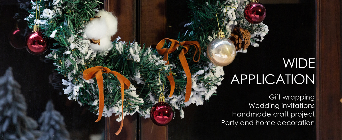 Terracotta velvet ribbon bows decorate a snowy holiday wreath with pinecones and colorful baubles.