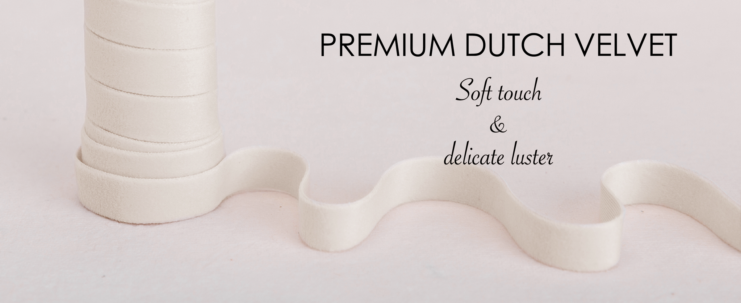 Ivory velvet ribbon wound on natural wooden spools with loose ribbon across pale textured fabric.