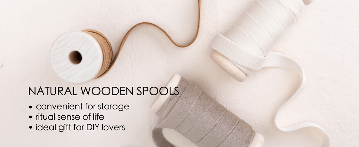 Assorted velvet ribbons in green, charcoal, white, taupe, brown, red and blue on wooden spools.