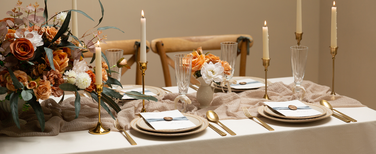 Dusty blue and ivory velvet ribbons accent place cards and glass stems on a candlelit dining table.