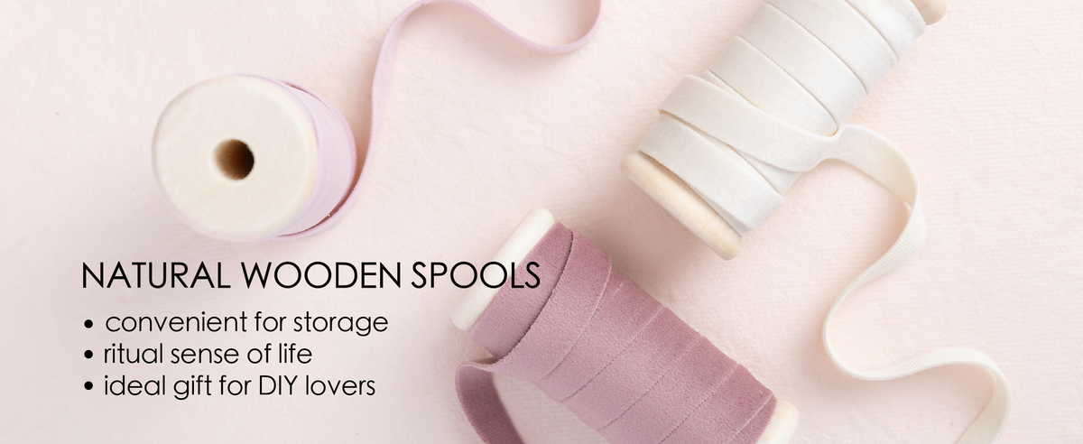 Pink and white velvet ribbon set unwound from natural wooden spools in a clean product detail scene