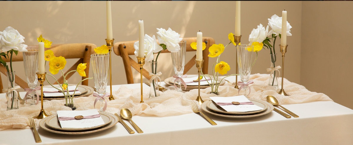 Pink and white velvet ribbon set styled across a dining table with flowers, candles, and place settings